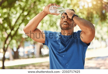 Fitness, outdoor and a man pouring water on face after exercise, training or running at a park. Tired Indian male athlete in nature for workout, run and break or cooling down with a splash in summer Royalty-Free Stock Photo #2310717425