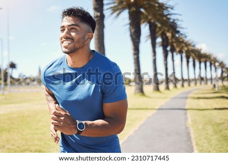 Fitness, smile and a man or runner outdoor for exercise, training or running at a park. Happy Indian male athlete in nature for a workout, run and cardio performance with a watch for progress or goal Royalty-Free Stock Photo #2310717445