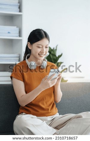 Asian women using mobile phone play Social media in home office.