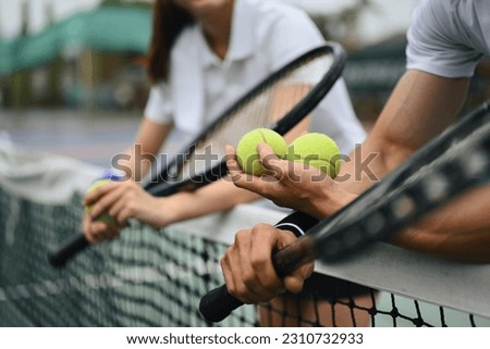 Cropped shot of male tennis coach hand holding balls, giving instructions to his student, standing by net at the court Royalty-Free Stock Photo #2310732933