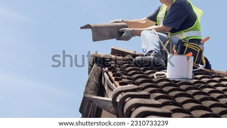 Worker man repairing eaves and tile of the old roof. Royalty-Free Stock Photo #2310733239