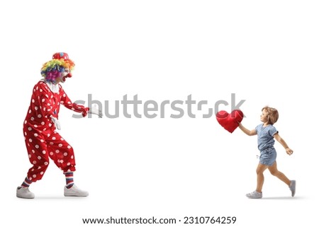 Full length shot of a little girl carrying a heart and running to hug a clown isolated on white background