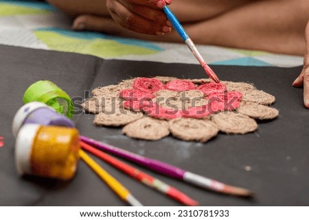 A female artist painting her door mat with brush to decoratye her home