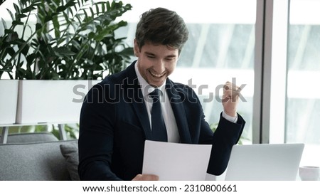 Overjoyed young Caucasian businessman feel euphoric reading good news in paper letter correspondence at workplace. Happy male boss or employee triumph with pleasant message or notice in paperwork. Royalty-Free Stock Photo #2310800661