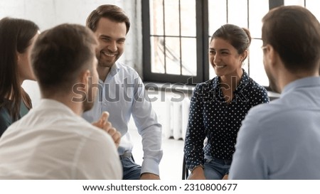 Happy millennial diverse group discussing personal problems, sharing experience, giving advice, help and comfort. Team engaged in teambuilding talking to coach, discussing successful project, laughing Royalty-Free Stock Photo #2310800677