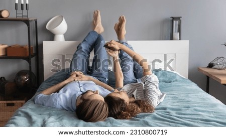 Happy millennial man and woman relax in bedroom have fun make self-portrait picture on smartphone. Young couple renters rest at in bed home use modern cellphone browsing wireless internet.