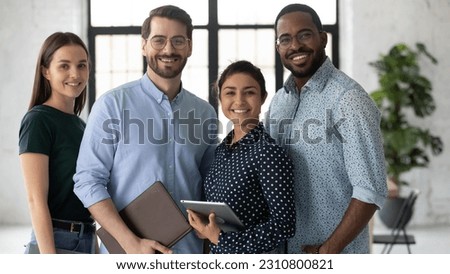 Group portrait of happy multiethnic united millennial team in modern office. Successful employees standing together, meeting in workspace, looking at camera and smiling Team work concept. Head shot Royalty-Free Stock Photo #2310800821
