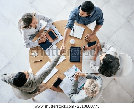 Meeting, handshake and overhead with a business team sitting around a table in the office at work. Partnership, thank you and welcome with male colleagues shaking hands in agreement of a b2b deal Royalty-Free Stock Photo #2310803773