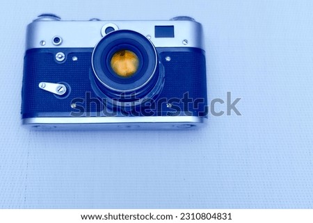 Old vintage film photo camera with lens isolated on pale blue                               
