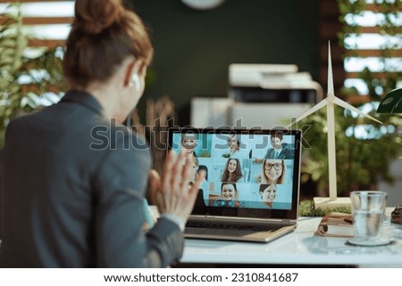 Seen from behind modern female with laptop having video meeting in modern office.