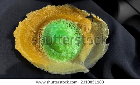 A photo of a traditional pancake of Jakarta is known as Kue Ape or Serabi Jakarta. This green street food is a pancake with soft and fluffy in the center that is surrounded by thin-crispy crepes. Royalty-Free Stock Photo #2310851183