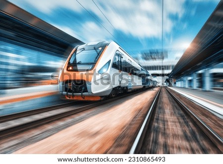 High speed train in motion on the railway station at sunset. Modern intercity passenger train with motion blur effect on the railway platform. Industrial. Railroad in Europe. Commercial transportation Royalty-Free Stock Photo #2310865493