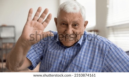 Hello. Headshot portrait of happy smiling grey haired elderly man pensioner looking at camera waving hand hi. Positive old grandfather making videocall greeting welcoming dialogue partner using webcam