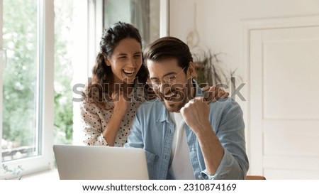 Overjoyed loving young bonding family couple looking at computer screen, getting email with amazing good news, celebrating online lottery betting gambling giveaway win, internet success concept. Royalty-Free Stock Photo #2310874169