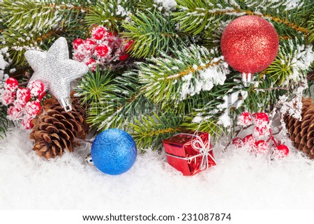 Christmas fir tree branch with holly berry and decor over snow
