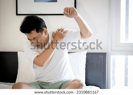 Asian middle aged man suffering from frozen shoulder,pain and stiffness,unable to move,difficulty lifting his arm,male people with calcific tendonitis or shoulder injuries,health care,medical concept Royalty-Free Stock Photo #2310881167