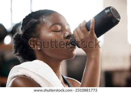 Black woman, fitness and drinking water at gym for sustainability, hydration or thirst after workout exercise. Thirsty African female person with drink for refreshment after cardio training indoors Royalty-Free Stock Photo #2310881773