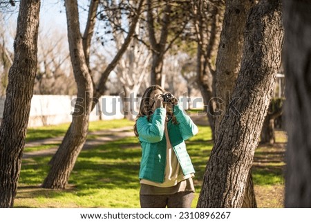 Girl with long hair.taking a picture outdoors.with a vintage camera.
