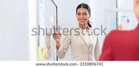 Businesswoman pointing towards graph and giving presentation explaining the idea to her business colleagues in the office. Group of Asian businesspeople brainstorm and work as team