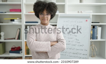Young african american woman teacher teaching maths lesson standing with arms crossed gesture at university classroom