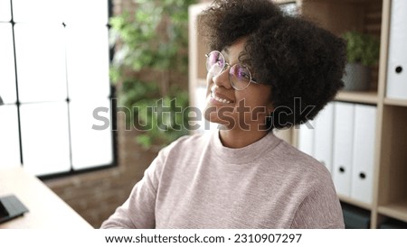 Young african american woman business worker smiling confident sitting on table at office