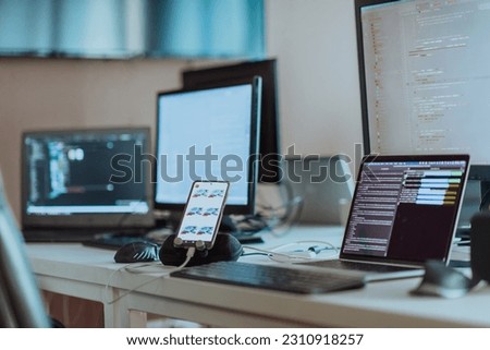 Computer screens running programming code in empty software developing agency office and computers parsing data algorithms in background. Neural network servers cloud computing in data room. Royalty-Free Stock Photo #2310918257