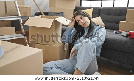 Young hispanic woman sitting looking tired at new home