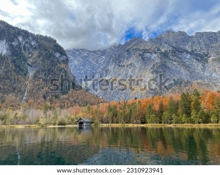The picture shows a boathouse on the shore of the tranquil Lake Königsee on a beautiful autumn day in front of the picturesque mountains of the Bavarian Alps near Berchtesgaden in Germany.