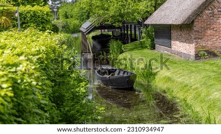 Small black wooden fishing boat in the canal at Giethoorn, Netherlands. Royalty-Free Stock Photo #2310934947