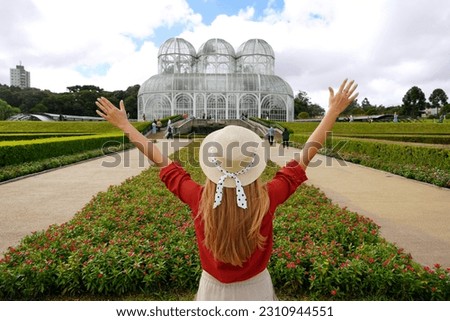 Tourism in Curitiba, Brazil. Back view of stylish traveler woman with raising arms in  botanical garden of Curitiba, Parana, Brazil. Royalty-Free Stock Photo #2310944551