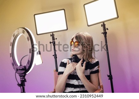 Young woman making photo or video content for social media with smartphone and light of ring lamp. Influencer makes broadcast communicates with followers in social networks. 
