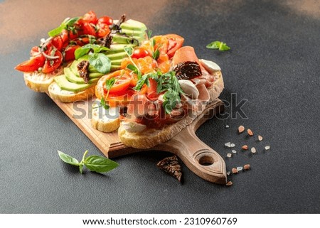a set of bruschetta with prosciutto, salmon, tomatoes and avocado on a wooden board, banner, menu, recipe place for text, top view,