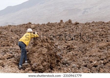 Teenage girl with a hat taking a picture, volcanic landscape, Tenerife