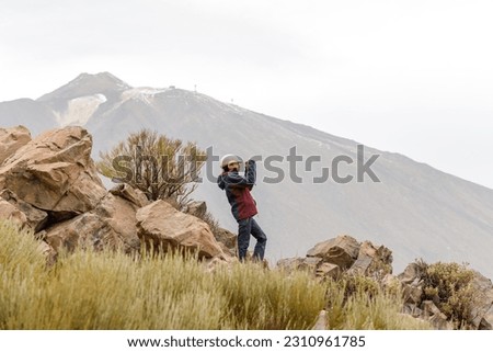 Teenage girl with a hat taking a picture, with the Teide volcano in the background, Tenerife