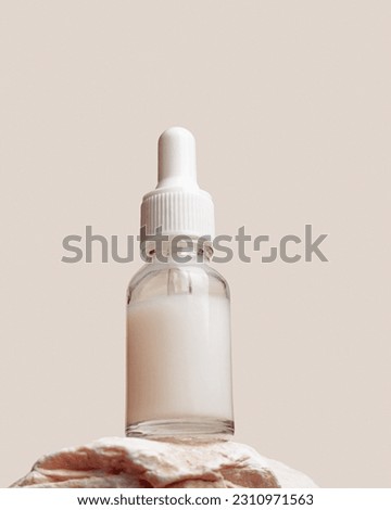 Glass dropper bottle with extract coconut or serum on stand from natural stones on beige background. Natural Organic Spa Cosmetic concept, cosmetic product mock up, minimal style. Hero view, copyspace Royalty-Free Stock Photo #2310971563