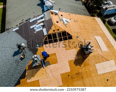 Apartment building roof underwent repairs that included installation of new shingles replacing old roof Royalty-Free Stock Photo #2310975387