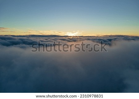 Aerial view from above at high altitude of dense puffy cumulus clouds flying in evening. Amazing sunset from airplane window point of view Royalty-Free Stock Photo #2310978831
