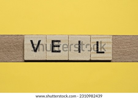 the word veil of gray small wooden letters lies on a yellow table
