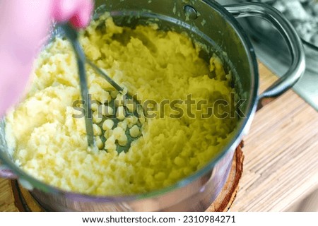 The hand of a person who makes mashed potatoes from potatoes. Pushes potatoes with the help of a special device. Royalty-Free Stock Photo #2310984271