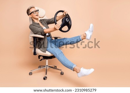 Full body size photo of overjoyed business woman boss riding steering wheel simulation game armchair isolated on beige color background