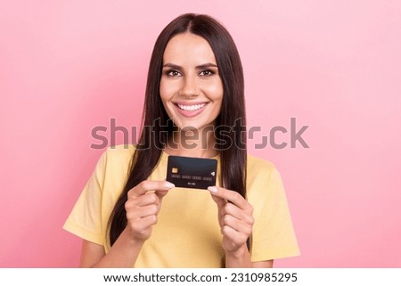Photo of adorable cheerful lady wear yellow t-shirt rising credit card smiling isolated pink color background