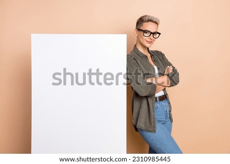 Photo of shiny adorable woman wear khaki shirt arms folded white poster emtpy space isolated beige color background