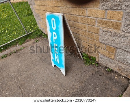 An old open sign sitting by a brick wall.