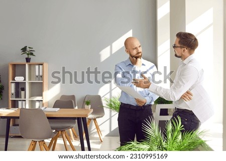 Two business men standing in office near the workplace discussing making successful deal or signing contract. Company employees talking and making great decisions with brainstorming on a meeting.