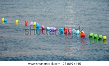 Colorful air balloons in a line floating on calm sea surface.