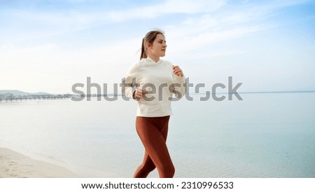 Slow motion of active and fit young woman running on the beautiful sandy beach, embodying the importance of physical activity and regular exercise Royalty-Free Stock Photo #2310996533