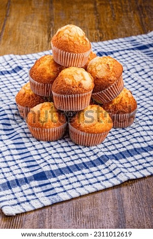 A Pile of Cupcakes on a Wooden Background and a Kitchen Rag