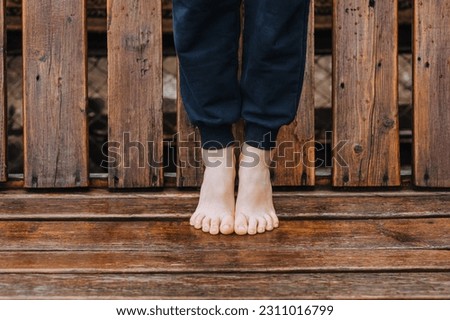 A little girl, a child stands barefoot on a wooden bench, doing yoga exercises. Photography, sports, health.