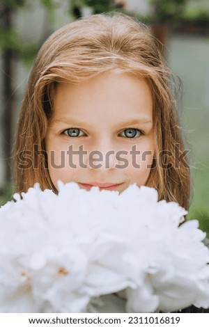 Photography, close-up face portrait of a red-haired beautiful girl, a child with white peonies flowers.