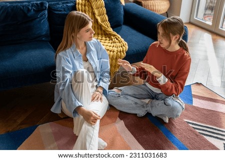 Close relations mother with teenager. Understanding mom sits on floor listen to teen girl sharing secrets, opinions gossiping like friend. Loving woman have pleasant conversation with daughter at home Royalty-Free Stock Photo #2311031683